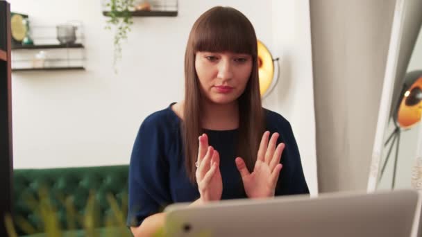 Молода кавказька позаштатна бізнес-леді сидить за столом і використовує свій ноутбук для онлайн відеоконференції з клієнтом . — стокове відео