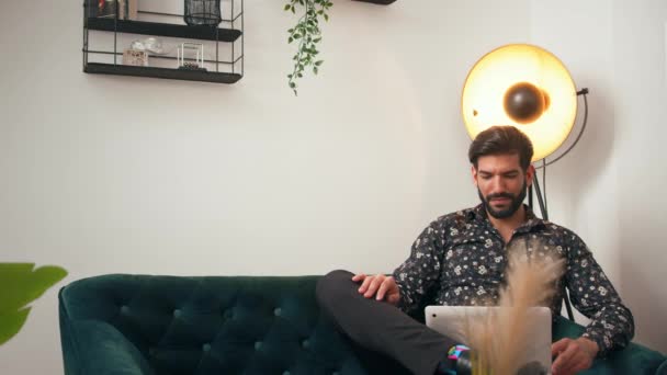 Kubanischer stylischer Mann in seinen Dreißigern sitzt in einem Wohnzimmer neben einer Lampe, hat ein Online-Meeting, redet und lacht. — Stockvideo