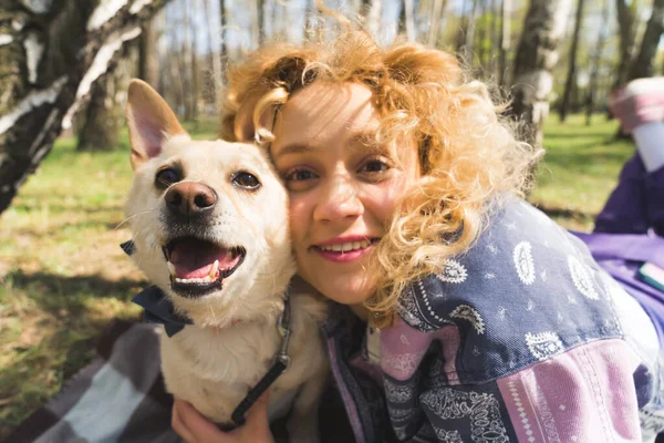 Porträtt av leende glad flicka med lockigt hår och hennes hund i parken — Stockfoto