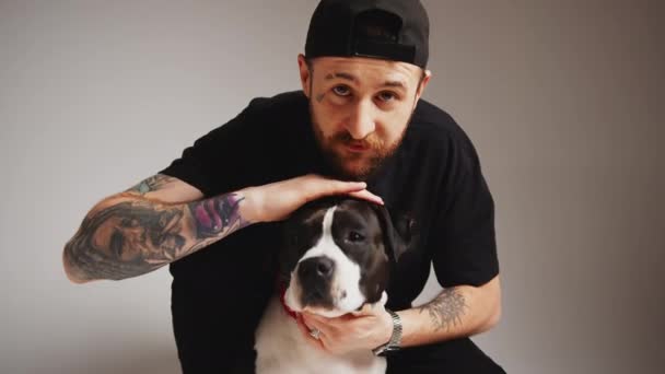 Gangster-like tattooed bearded caucasian dog owner guy in black clothes petting his cute pedigree dog. — Stock Video