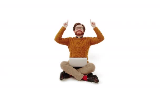 Jóképű fehér szakállas barnás férfi, puha narancssárga kötött pulóverben, laptoppal a térdén, felfelé mutat a fénymásolótérben. Hirdetési ötlet. — Stock videók