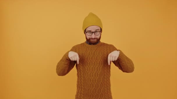 Kolla in annonsen nedan. Skägg kaukasier kille i en mössa pekar ner för att kopiera utrymme över gul bakgrund. — Stockvideo