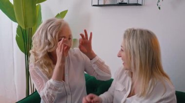 İki orta yaşlı beyaz kadın birlikte eğleniyor, el ve parmaklarıyla baykuş işareti yapıyorlar. İç daire fotoğrafı..