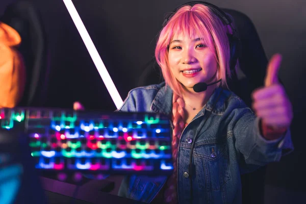 Joven jugadora asiática en auriculares que muestra el teclado iluminado y el concepto de espacio de copia pulgar hacia arriba —  Fotos de Stock