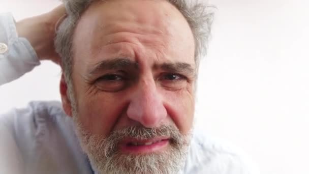 Gros plan d'un vieil homme barbu caucasien dégoûté qui se gratte la tête et regarde ses cheveux. Concept de pellicules. — Video
