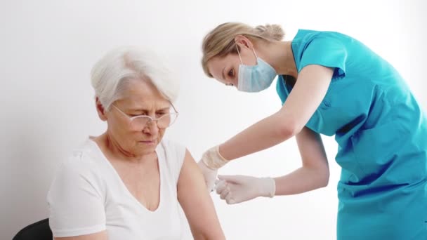 Молодая кавказская медсестра со шприцем, делающая укол для пожилой женщины — стоковое видео