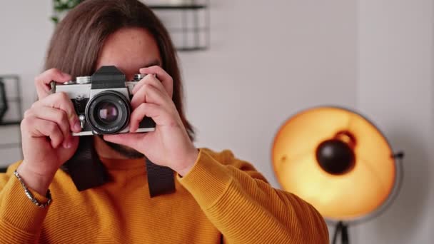 Indoor portret van een jonge volwassen blanke mannelijke fotograaf die foto 's maakt en lacht naar de camera. Modern beroepsbegrip. — Stockvideo