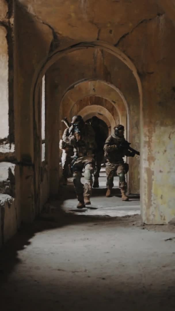 Tiro vertical de uma equipa militar em perseguição de camuflagem num edifício abandonado. Conceito de missão secreta. — Vídeo de Stock