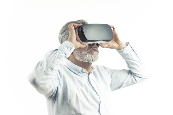 Virtual Reality concept. Blanke man van middelbare leeftijd met grijs haar in een hemd met een professionele VR-bril die ze in verbazing aanraakt. Geïsoleerd over witte achtergrond. — Stockfoto
