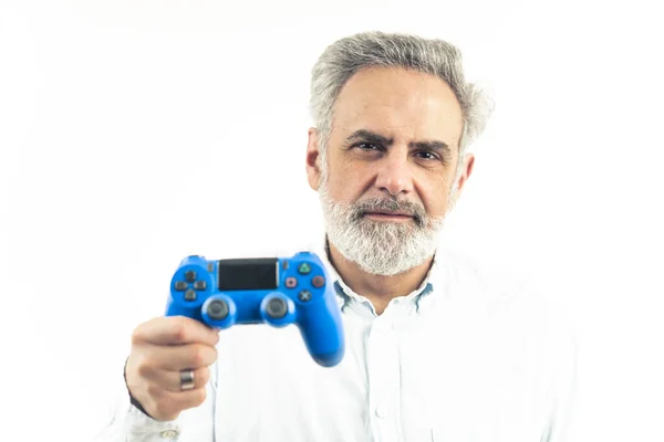 Knappe volwassen blanke man met zilver haar en een baard die naar de camera kijkt en een blauwe gamepad controller vasthoudt - geïsoleerd op een witte achtergrond. — Stockfoto