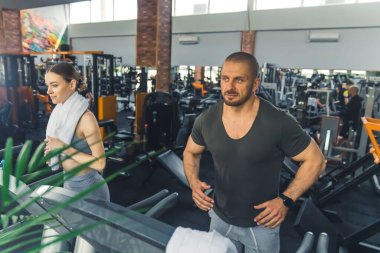 Beden eğitimi zamanı. En sevdikleri spor salonunda profesyonel koşu bandı kullanan iki kişi. Kardiyo egzersizleri.