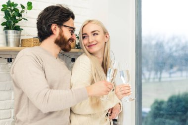 Çekici, beyaz bir çiftin şarap kadehleriyle birbirlerine sevgiyle baktıkları bir mutfakta çekilmiş bir fotoğraf. Kutlama konsepti. Yüksek kalite fotoğraf