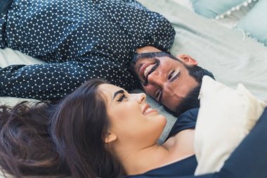 Çekici genç bir çift yatakta uzanıyor ve birbirlerine romantik bakışlar atıyorlar, tatlı çift kavramı.