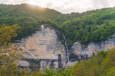 Orman kayalıklarında ince bir şelalenin görkemli görüntüsü.