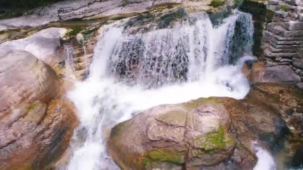 Cascada pequeña y rápida en enormes salientes rocosos de montaña, tiro aéreo — Vídeo de stock