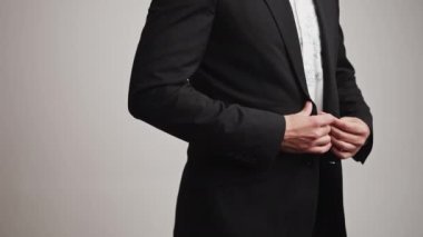 Resmi bir kıyafet giymiş, ceketinin düğmelerini ilikleyen tanınmayacak kadar zarif bir adam. Beyaz arka planda yatay stüdyo çekimi. Yüksek kalite 4k görüntü