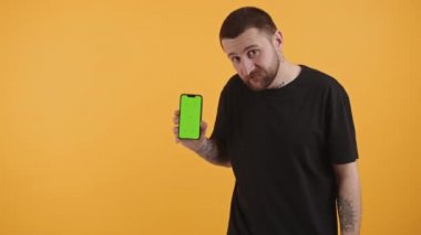 Kollarında dövmeleri olan çekici bir milenyum telefonu yeşil ekranlı gösteriyor. Fotoğraf stüdyosunun orta boy fotokopi çekimini izliyorlar. Yüksek kalite 4k görüntü