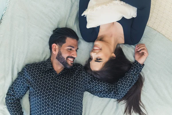 可愛いラテン系のカップルがベッドの上に横たわり お互いを見ながら幅広く笑顔 関係の概念 高品質の写真 — ストック写真