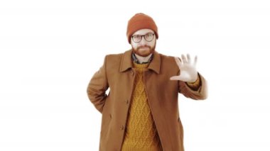 Bereli komik, komik, iyi giyimli, beyaz sakallı beyaz bir adam etrafta aylak aylak dolanıp hediyesini beyaz arka planda kameraya veriyor. Yüksek kalite 4k görüntü