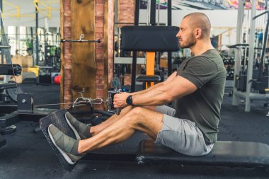 Spor salonundaki kel, beyaz vücutlu adam egzersiz yapıyor. Bacak ve kol egzersizi. Kas yüzdesi konsepti. Yüksek kalite fotoğraf