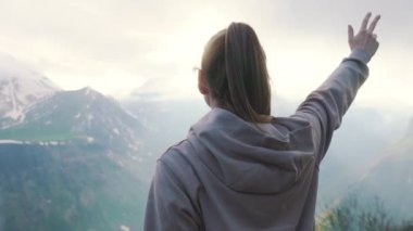 Kafkasya dağlarının tepesinde elini kaldıran genç bir kız, Gürcistan, Avrupa. Yüksek kalite 4k görüntü