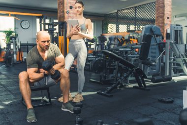 Kolları üzerinde çalışıyor. Spor salonunda spor hocasıyla çalışan kaslı bir delikanlının uzun pozu. Yüksek kalite fotoğraf