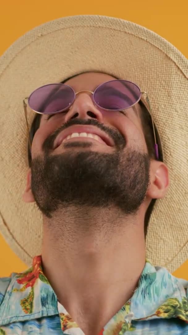 オレンジの隔絶された背景の上に頭を揺らしている現代のサングラスと夏の服を身に着けている若い男性のクローズアップポルトガル スタジオショット 高品質4K映像 — ストック動画