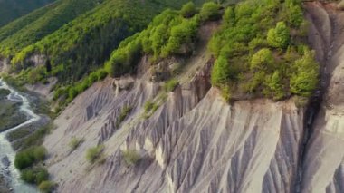 Yeşil bitki örtüsüyle kaplı dik bir uçurumun yukarıdan görünen görüntüsü. Ayakta bir nehir. Yüksek kalite 4k görüntü