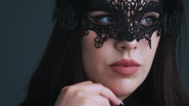 Kapalı stüdyo portresi. Güzel, baştan çıkarıcı, siyah saçlı, paspas ruju ve güzel siyah dantelli bir maskesi olan beyaz bir kadın. Yüksek kalite 4k görüntü