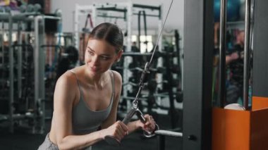 20 'li yaşlarda oldukça yoğun ve çekici bir kadının sırt kaslarını çalıştırmak için bir makineye tutunurken orta boy bir fotoğrafı. Yüksek kalite 4k görüntü