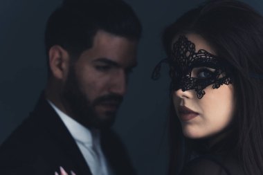 Siyah dantelli göz maskeli esrarengiz beyaz saçlı kız takım elbiseli yakışıklı sakallı bir adamın önünde kameraya bakıyor. - Evet. Yüksek kalite fotoğraf