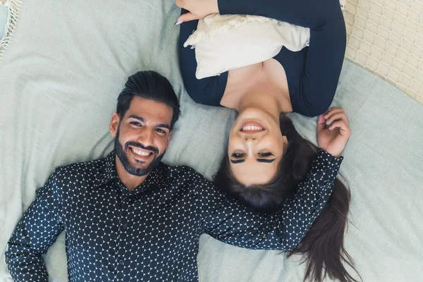 ハンサムな髭の男と彼の美しい長髪のガールフレンドのベッドの上に横たわる 笑顔とカメラを見て 幸せな関係だ 高品質の写真 — ストック写真