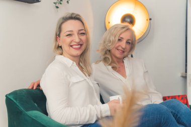 İki neşeli kadın sohbet ediyor ve ev ortamında kahve içiyor. Yakın oturma odasında. Yüksek kalite fotoğraf