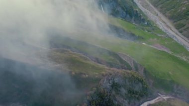 Bulutlarla kaplı Kafkasya dağlarının tepe üstü manzarası ve uzak askeri yol, Stepantsminda, Georgia. Yüksek kalite 4k görüntü
