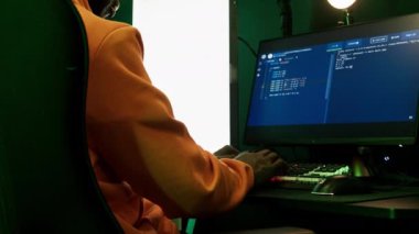 Sarı kapüşonlu Afro-Amerikan bir adamın portresi renkli ışıklı klavye, programlama ya da internette sörf yapıyor. Yüksek kalite 4k görüntü