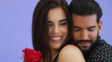 Güzel bir çiftin yakın plan portresi sevgilerini paylaşıyor, birbirlerine gülümsüyor ve menekşe arka planda birbirlerinin gözlerinin içine bakıyor. Yüksek kalite 4k görüntü