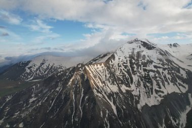 Tüylü bulutların yanındaki güzel siyah beyaz dağ zirvesi. Yüksek kalite fotoğraf