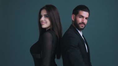 İki kişi, güzel uzun saçlı beyaz kız ve takım elbiseli sakallı Kübalı adam gri arka planda sırt sırta duruyorlar. Yüksek kalite 4k görüntü