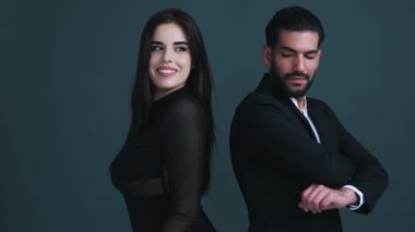 İki gülen güzel insan - heteroseksüel bir çift - sırt sırta vererek. Gri arka plan. Stüdyo çekimi. Uzayı kopyala Yüksek kalite 4k görüntü