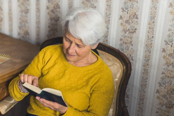 cute senior woman reading the Bible medium shot living room religion and spirituality concept. High quality photo