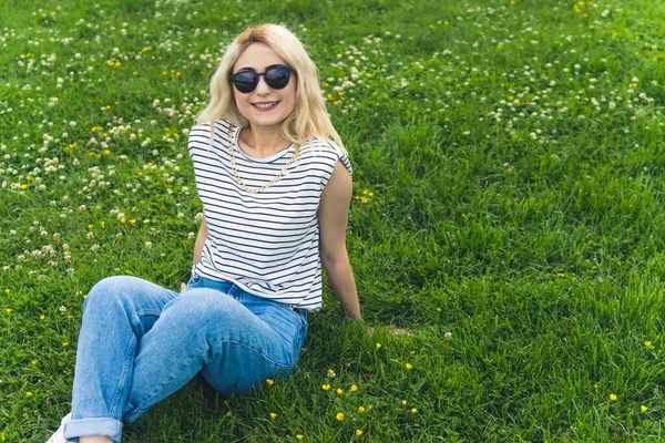 Blond Caucasian Girl Leaning Green Grass Smiling Camera Medium Full — Stock Photo, Image