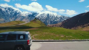 Gürcistan 'ın Kafkasya dağlarındaki Gergeti Trinity Kilisesi ve otoparkın insansız hava aracı görüntüleri. Yüksek kalite 4k görüntü