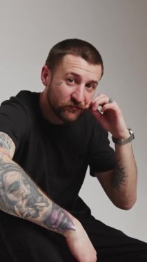 dikey video genç adam bıyığına dokunur ve yüzünü el siyahı kıyafetlerle kaplar. Yüksek kalite 4k görüntü