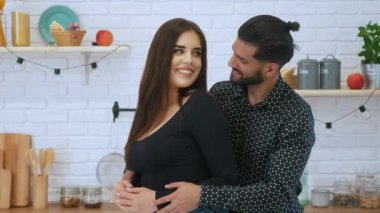 Sevimli heteroseksüel çift mutfakta sarılıp sırıtan ve kameraya bakan iki yetişkin Avrupalı. Yüksek kalite 4k görüntü