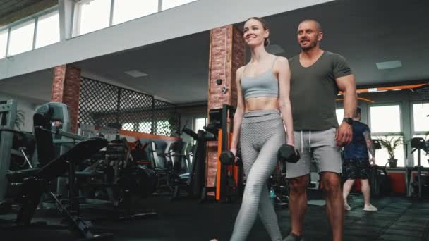 Erkek Antrenörü Tarafından Gözlemlenen Spor Salonunda Dambıllarla Egzersiz Yapan Sarışın — Stok video