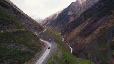 Dağlarda virajlı bir off-road pisti ve içinden geçen bir araba. Hava aracı görüntüsü. Yüksek kalite 4k görüntü