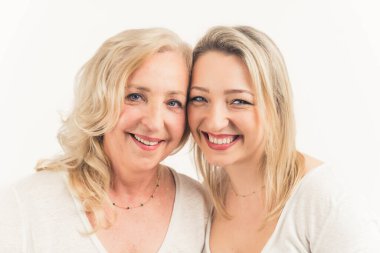 30 'lu yaşlarındaki sarışın Avrupalı güzel kadınlar beyaz kıyafetler giyip kameraya bakıyor ve başlarını birbirine yaslıyorlar. Stüdyo çekimi. Yüksek kalite fotoğraf