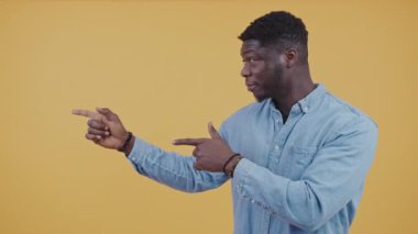 Afro-Amerikalı adam önce solu, sonra kendini işaret ediyor ve arka plan sarı fotokopi stüdyosunun çekimini onaylıyor. Yüksek kalite 4k görüntü