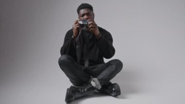 Yakışıklı Afro-Amerikalı bir adam fotoğraf çekiyor ve kamerayı kontrol ediyor. Gri arka plan izole edilmiş fotokopi alanı. Yüksek kalite 4k görüntü