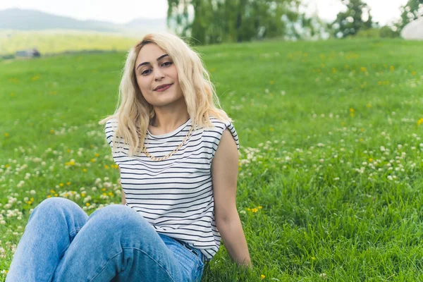 Średni Pełny Strzał Blondynki Białej Dziewczyny Siedzącej Zielonej Trawie Uśmiechającej — Zdjęcie stockowe